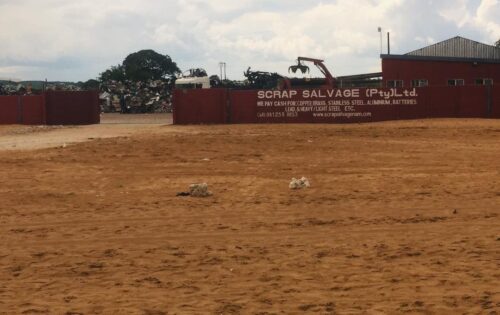 A large red building with "SCRAP SALVAGE (Pty) Ltd." written in white, advertising that they pay cash for various metals.